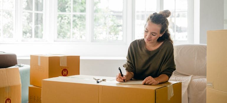 Woman signing box near large window in sunlight at home